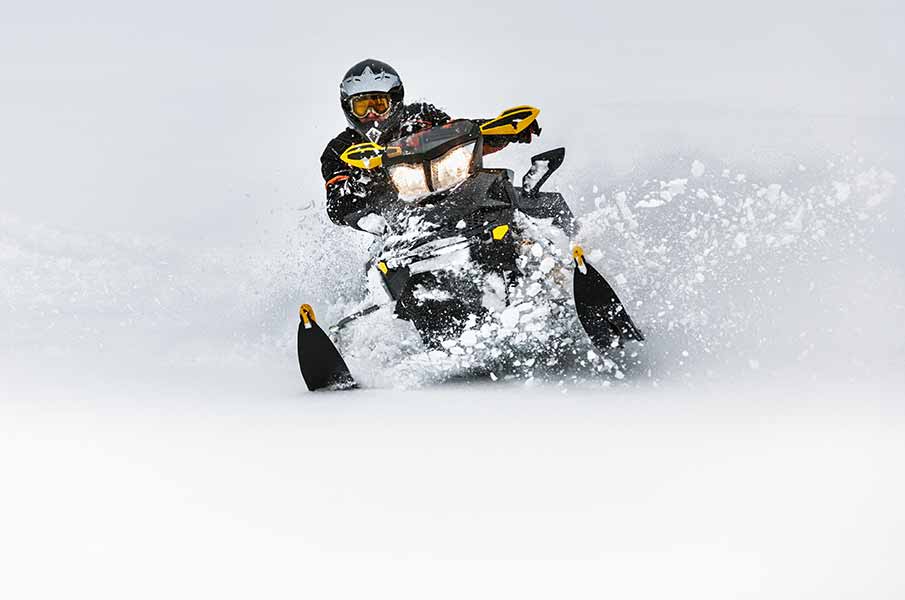 In deep snowdrift snowmobile rider make fast turn